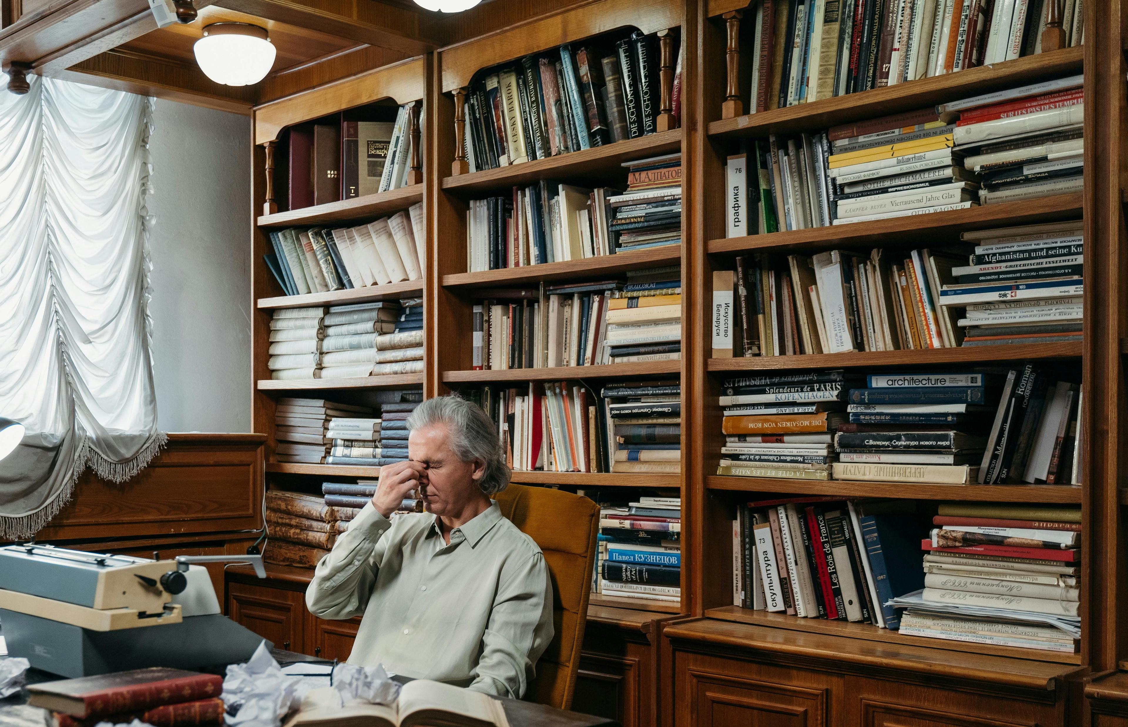 A molecular model made of silver rods and dark blue spheres stands on a sheet of paper with scientific sketches. The surroundings with laptops and office materials convey a high-tech research atmosphere.